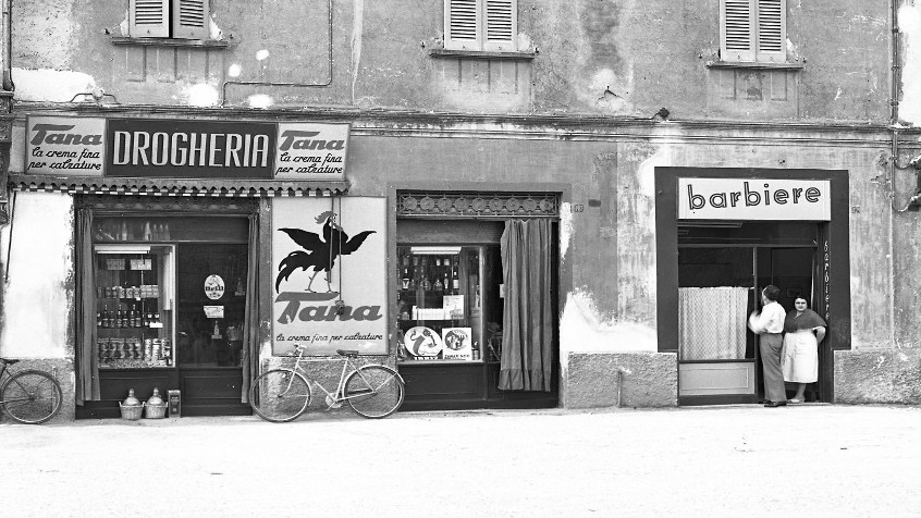 Pavia, palazzo via Trieste, ora viale Indipendenza 10, vetrine di una drogheria e di un barbiere, fine 1940 (CHL A_3_17_014)